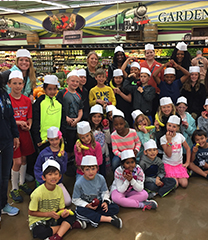 Group of children in a grocery store wearing paper hats